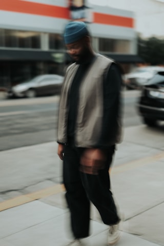 a man walking down a sidewalk next to a street