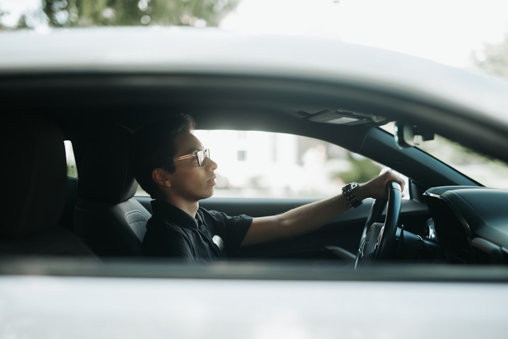 a man sitting in a car with his hand on the steering wheel