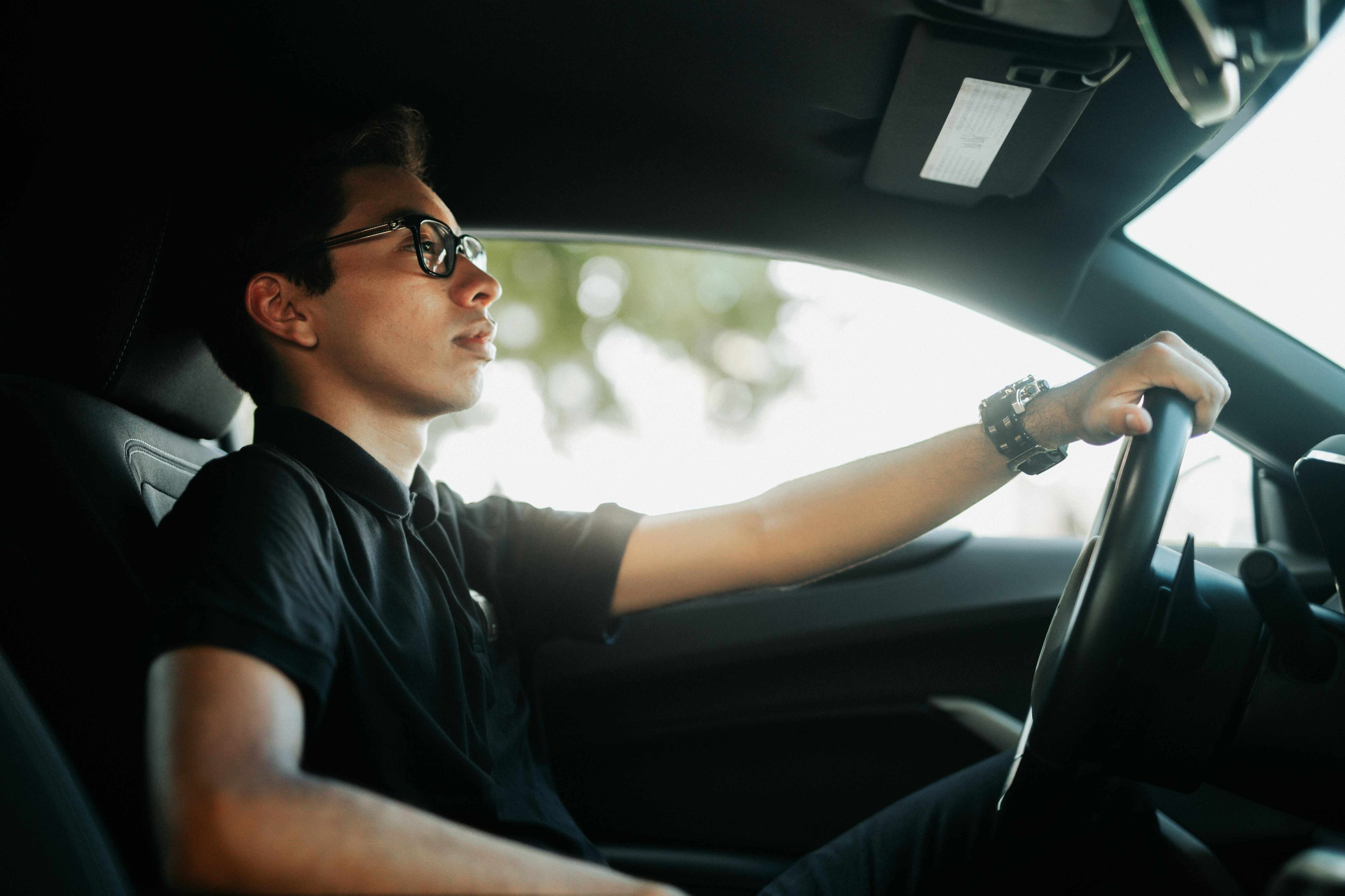 a man driving a car with his hand on the steering wheel
