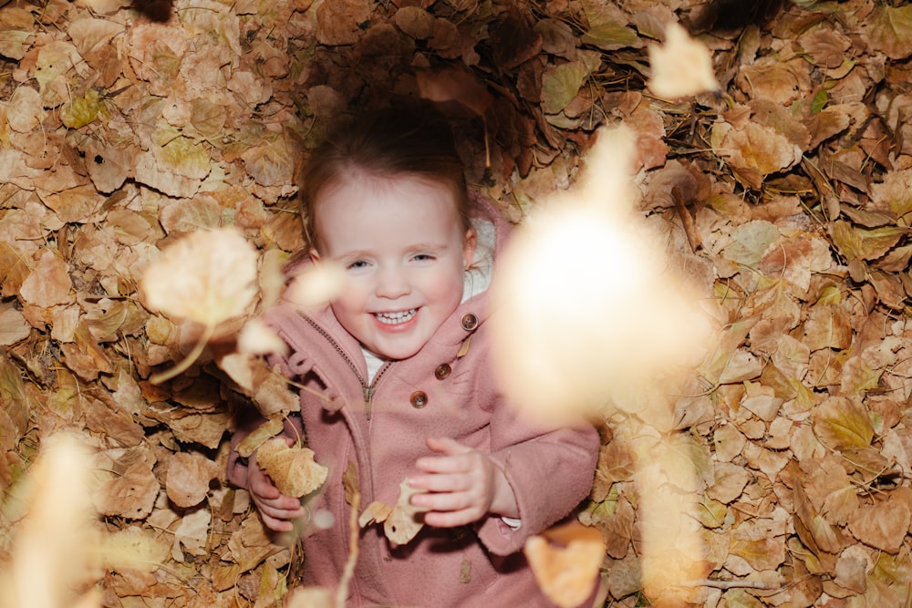 a little girl that is standing in a pile of leaves