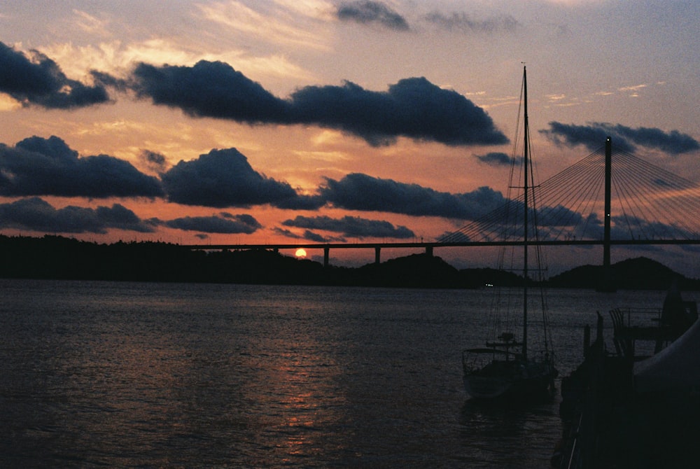 a sunset view of a bridge over a body of water