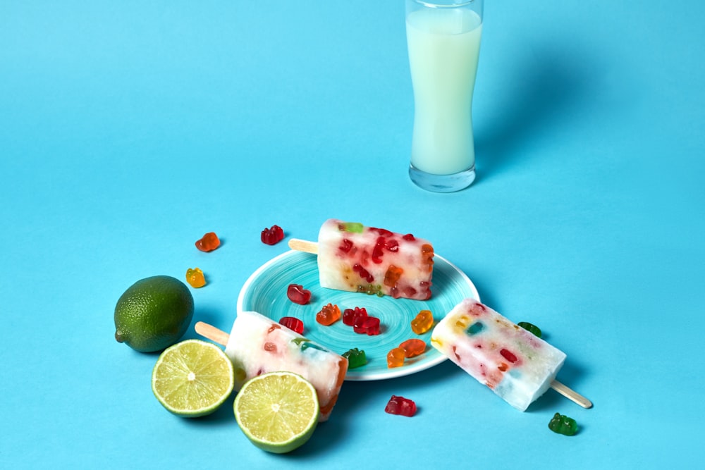 a plate of fruit pops next to a glass of milk