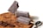 Three chocolate popsicles are arranged on a wooden platter. One popsicle has a bite taken out of it and is leaning against another. Chocolate shavings and pieces of chocolate are scattered on the platter, and a spoon is placed beside them.