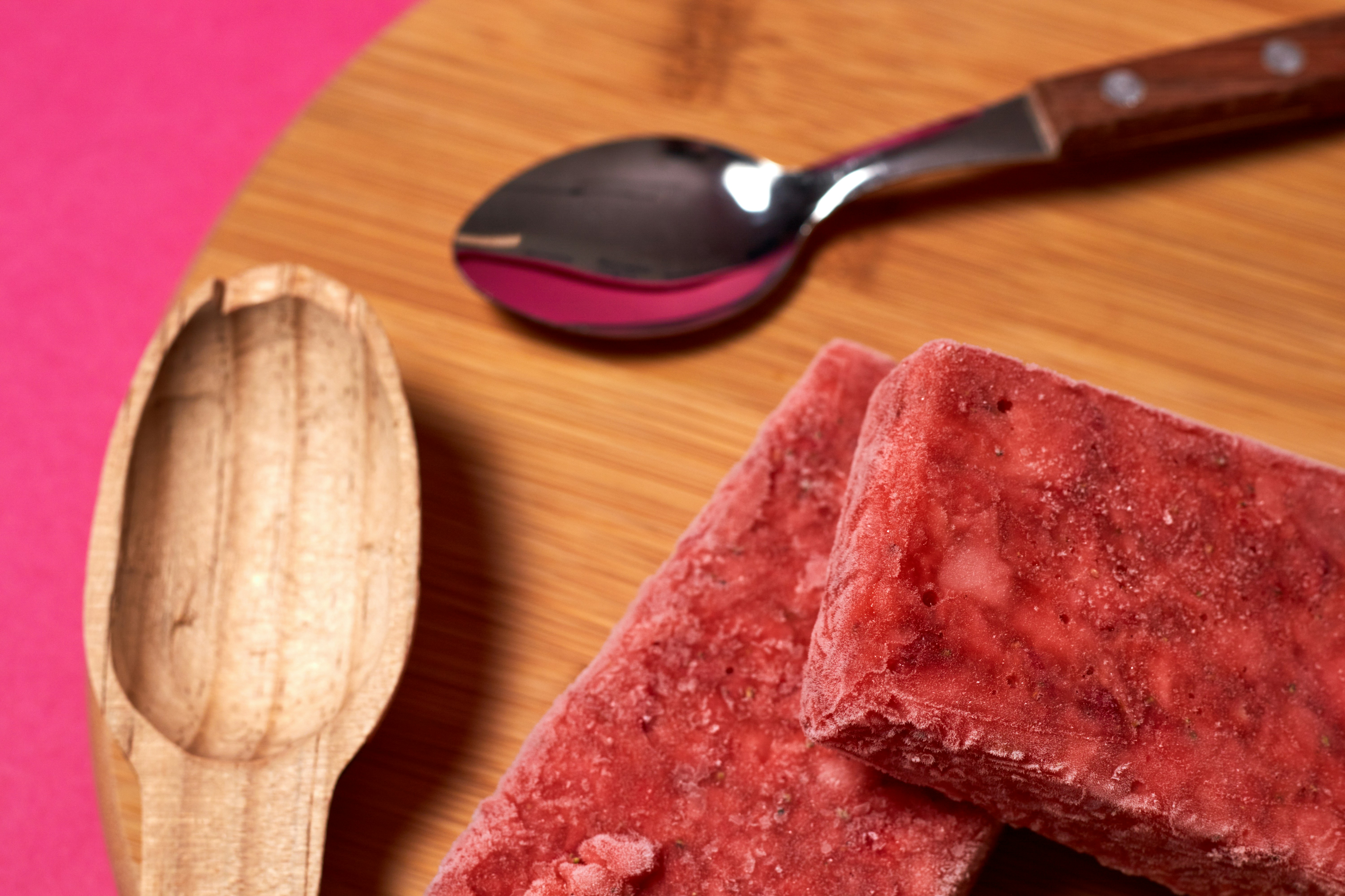 a close up of a wooden spoon and some food on a table