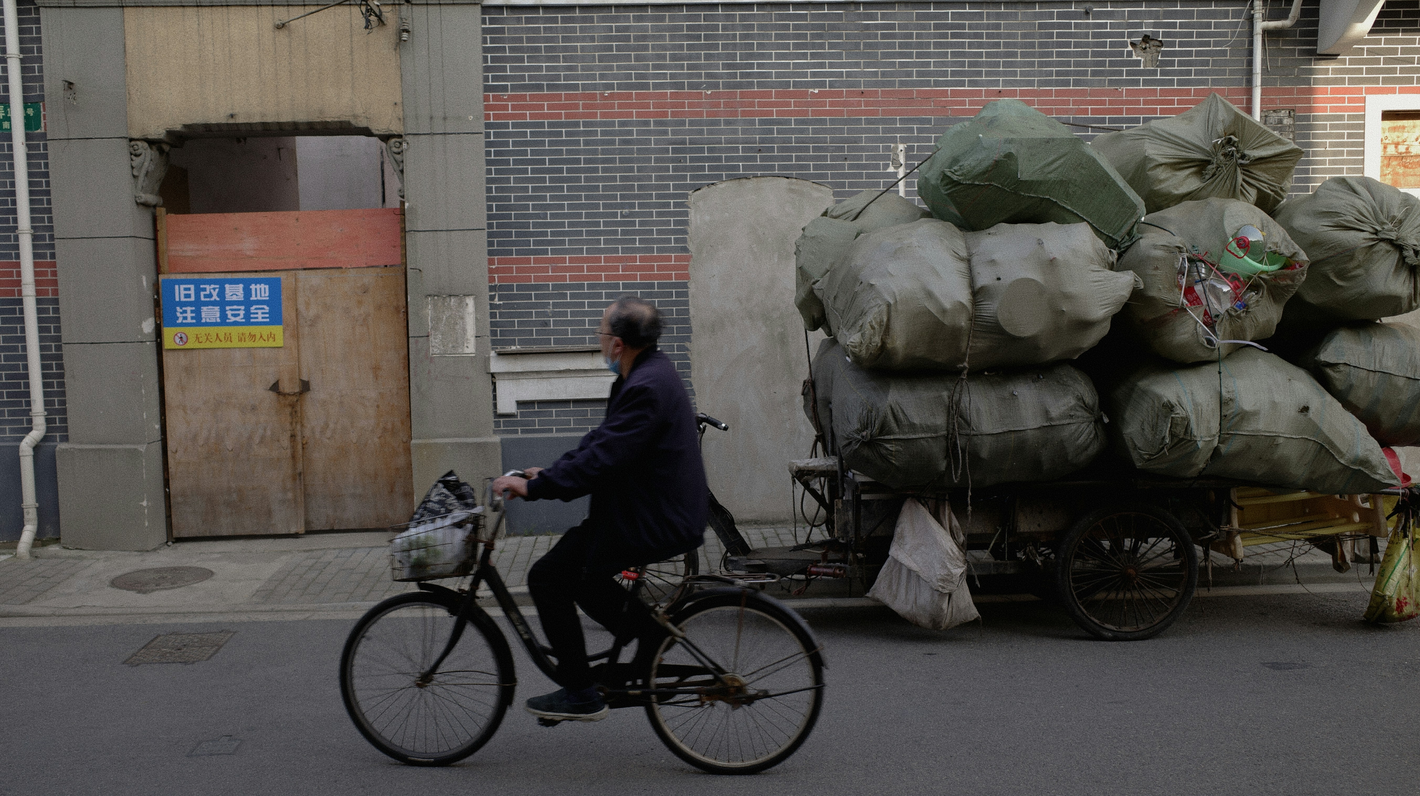 Un hombre andando en bicicleta por una calle junto a una pila de bolsas