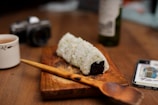 a wooden cutting board topped with a piece of sushi