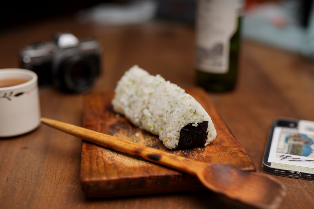 a wooden cutting board topped with a piece of sushi