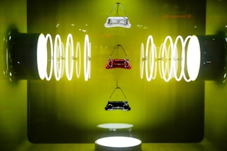 Three handbags are suspended against a vibrant green backdrop, surrounded by a series of illuminated circular rings on both sides, creating a symmetrical and futuristic display.