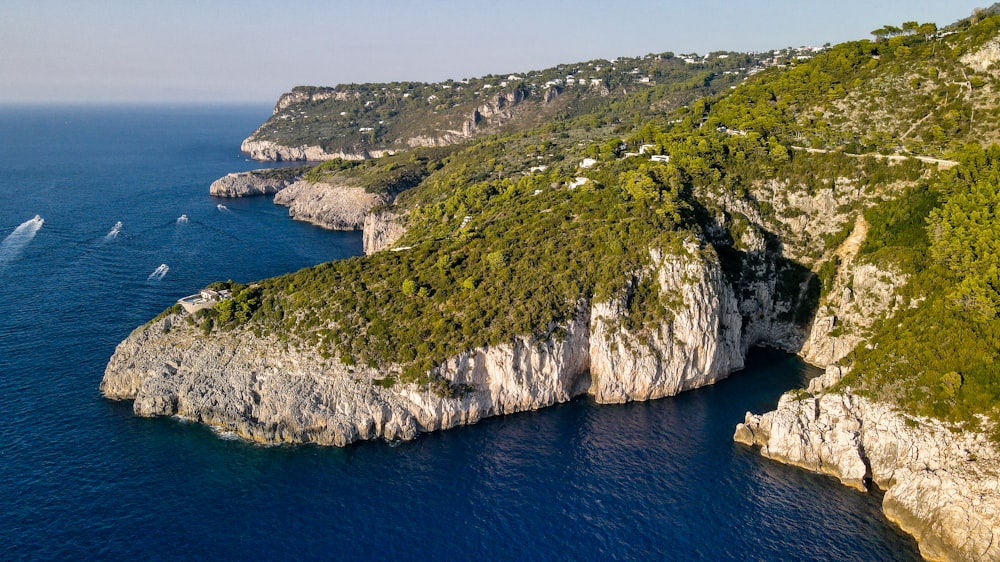 an aerial view of a cliff with a boat in the water