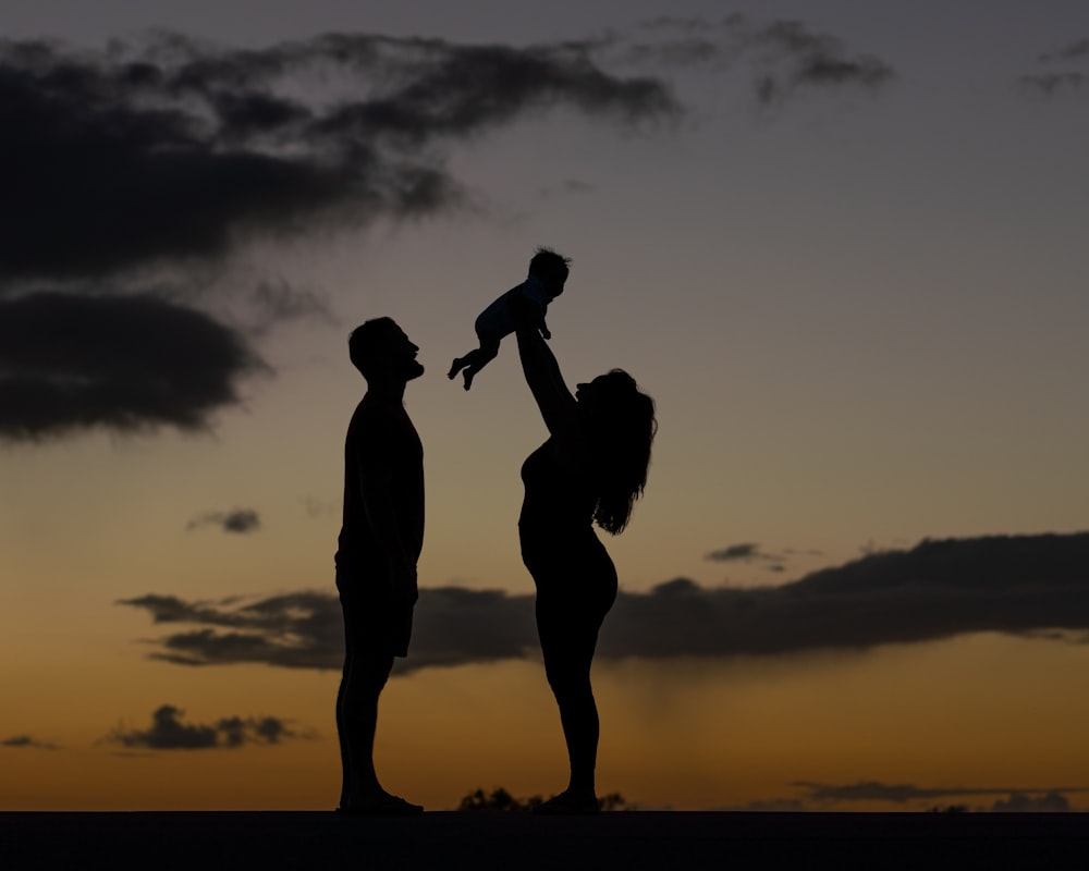 a silhouette of a man and a woman holding a baby