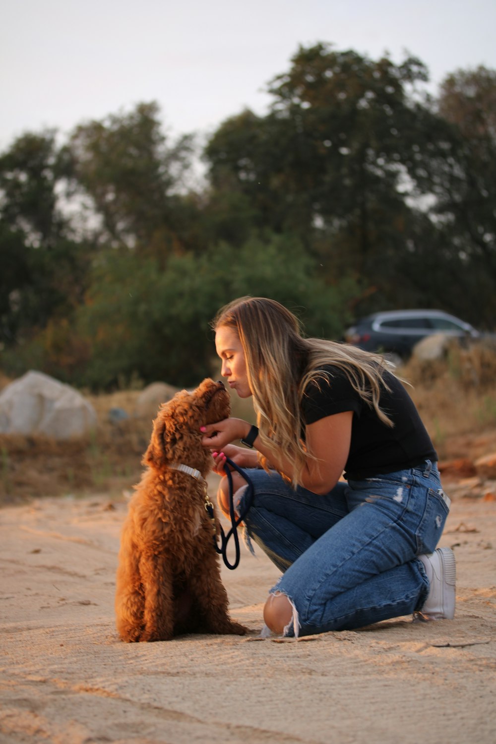 a woman kneeling down next to a brown dog