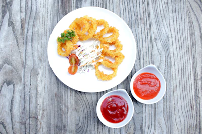 Golden crispy onion rings stacked next to a bowl of creamy coleslaw.