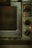 An old, well-used oven with dials and settings for different cooking temperatures and modes. The oven's metal exterior appears worn and dirty, likely from frequent use over time. There is a small red light indicating that part of the appliance is on.