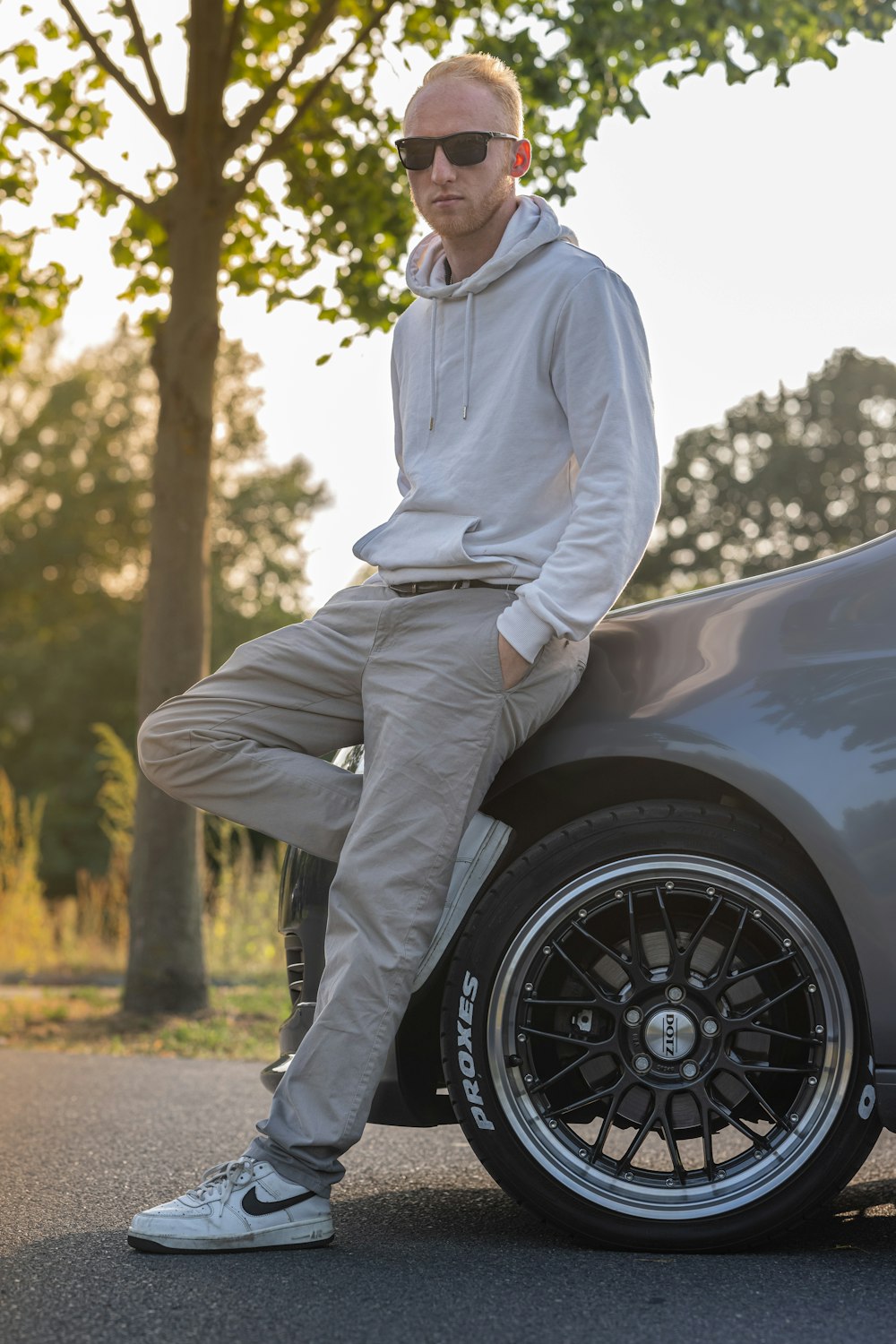 a man sitting on the hood of a sports car