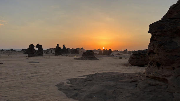 A vibrant desert sunset with a group of friends gathered around a glowing fire sculpture.