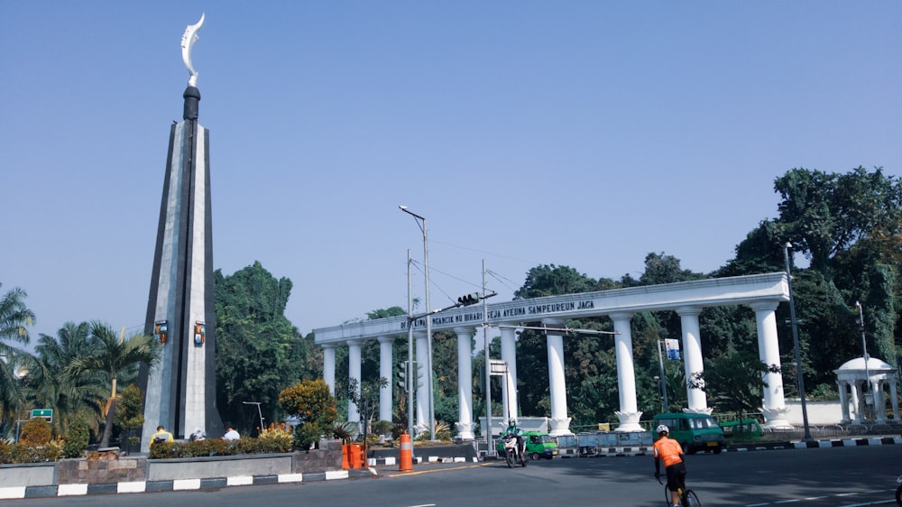 a man riding a bike down a street next to a tall white building