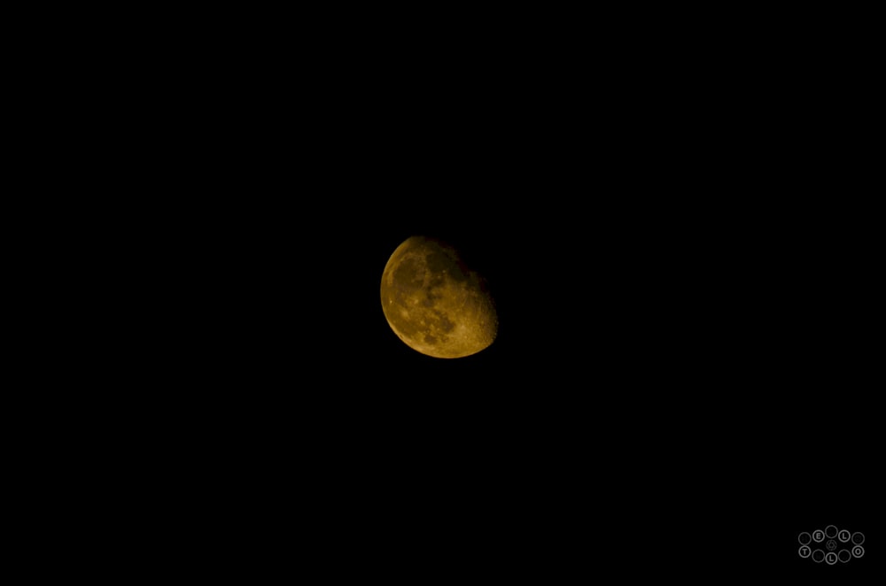 a yellow moon is seen in the dark sky