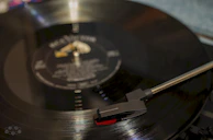 Close-up of a vinyl record spinning on a vintage turntable with African patterns reflected.