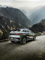 Side profile of a shiny SUV with a scenic mountain background.
