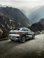 A robust SUV glistening under natural light with a scenic mountain backdrop.