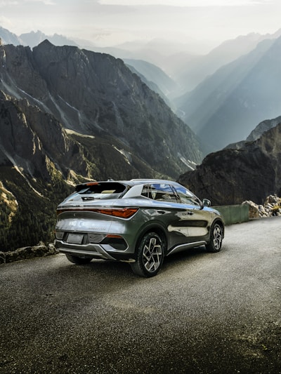 A shiny Skoda Superb 4x4 parked on a rugged mountain trail at sunset.