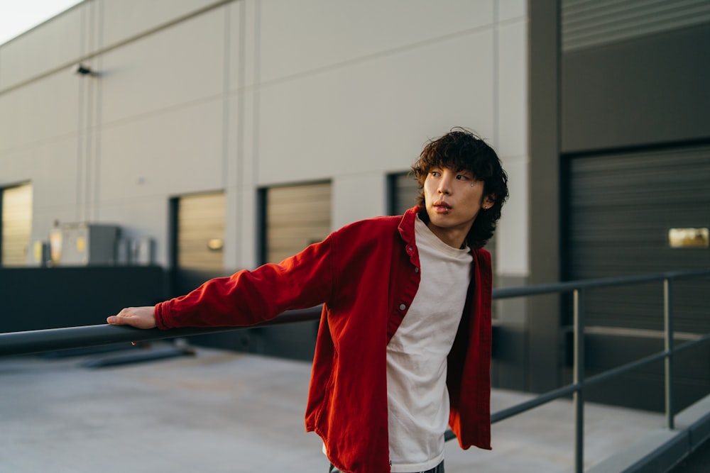 a man in a red jacket leaning on a rail