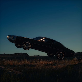 Dynamic shot of the car leaping over a dirt jump, wheels off the ground against a clear sky.