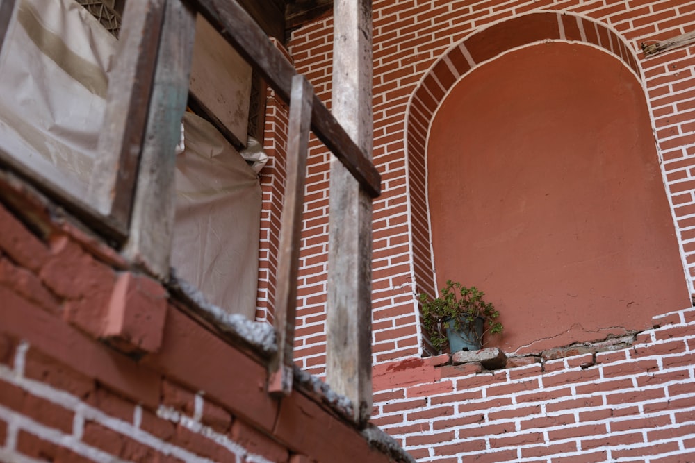 a brick building with a window and a potted plant