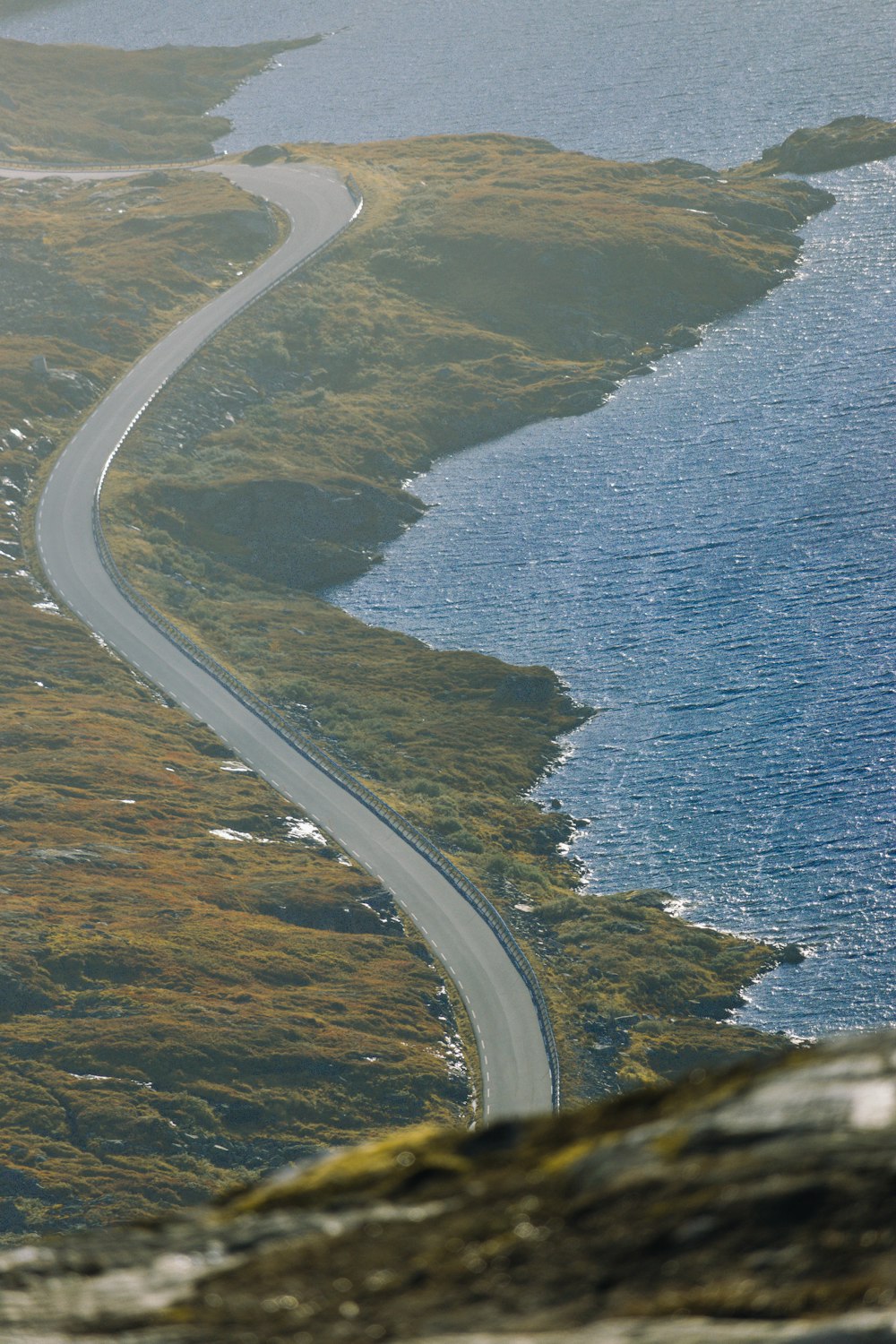 an aerial view of a winding road next to a body of water
