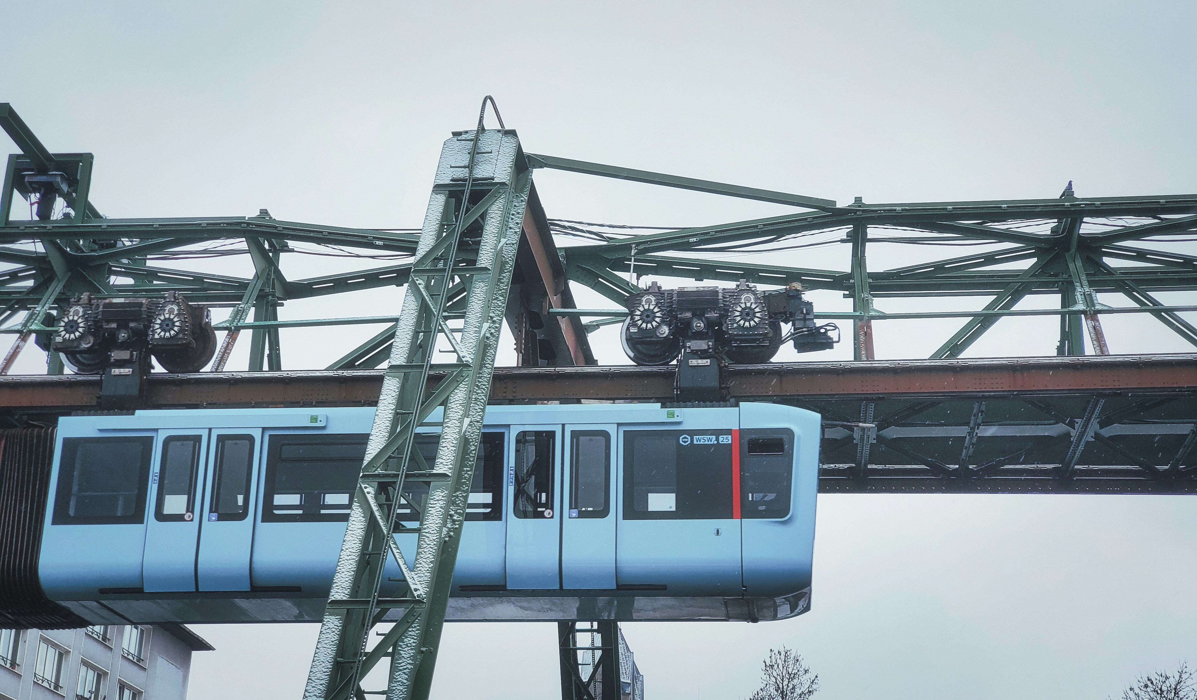 a blue train traveling over a bridge next to tall buildings