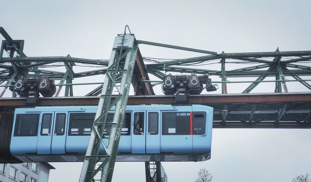 Un treno blu che viaggia su un ponte accanto a edifici alti