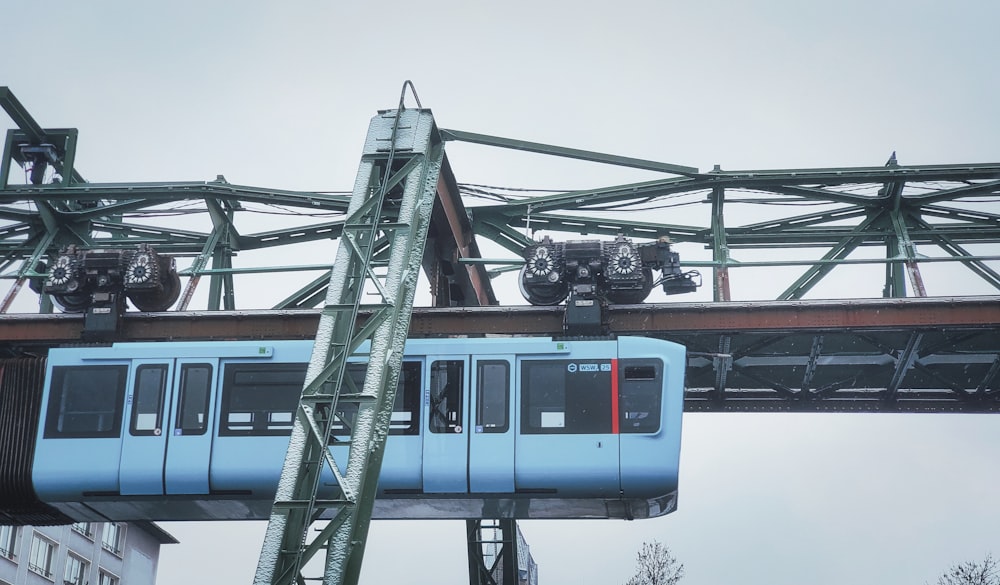 Un tren azul que viaja sobre un puente junto a edificios altos