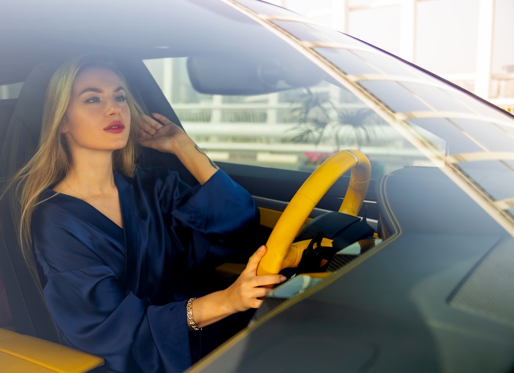 a woman sitting in a car holding a steering wheel