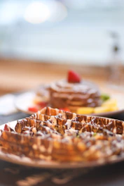 A close-up of a golden waffle topped with fresh strawberries and drizzled with rich chocolate sauce.