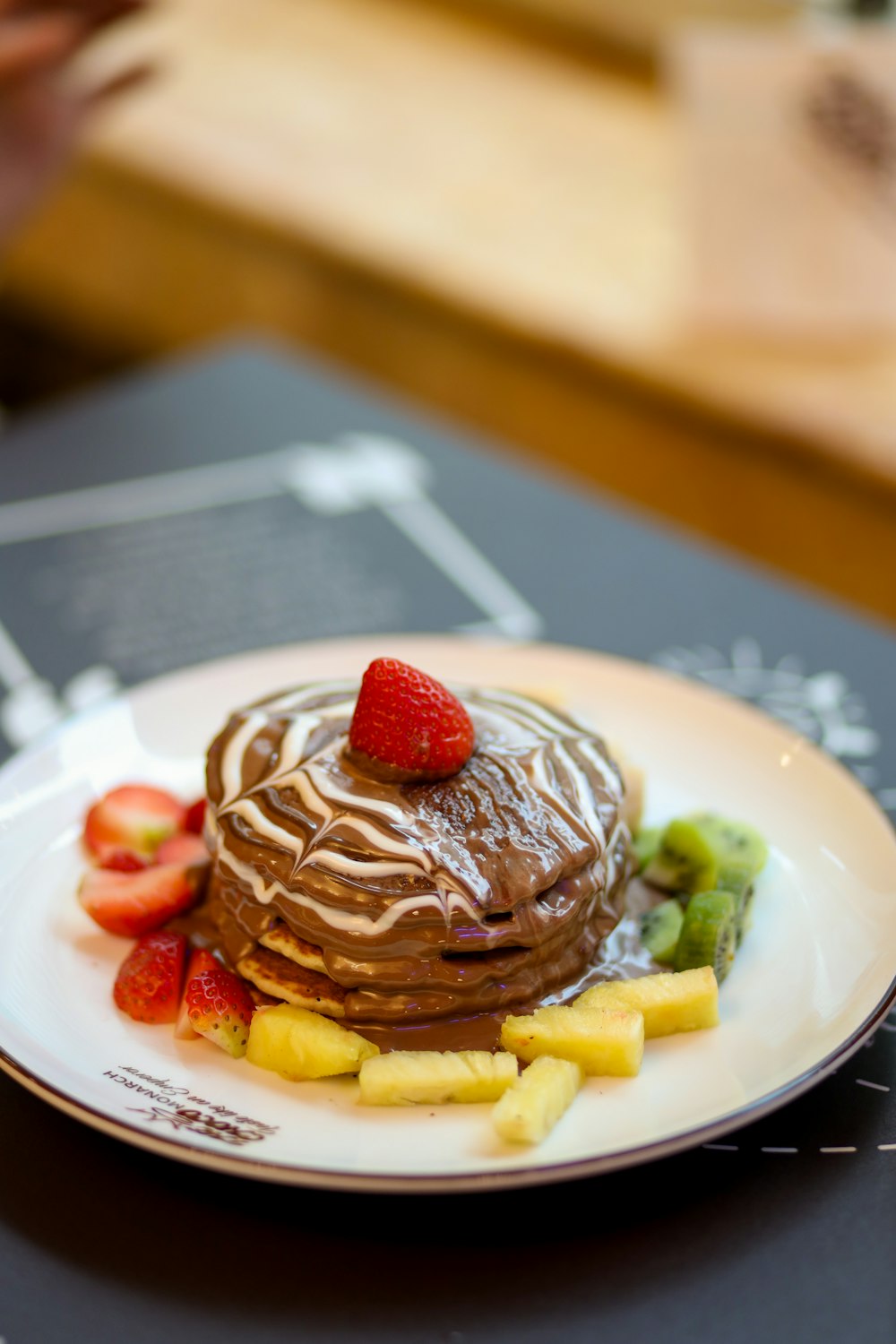 a white plate topped with a stack of pancakes covered in chocolate frosting and fruit