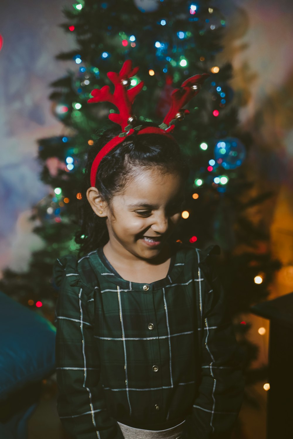 a little girl standing in front of a christmas tree