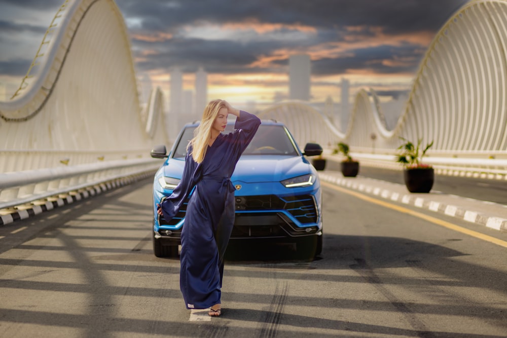 a woman leaning on the hood of a blue car