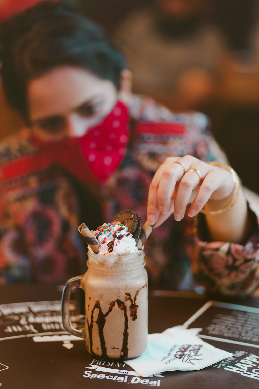 a woman wearing a red bandana eating a chocolate milkshake