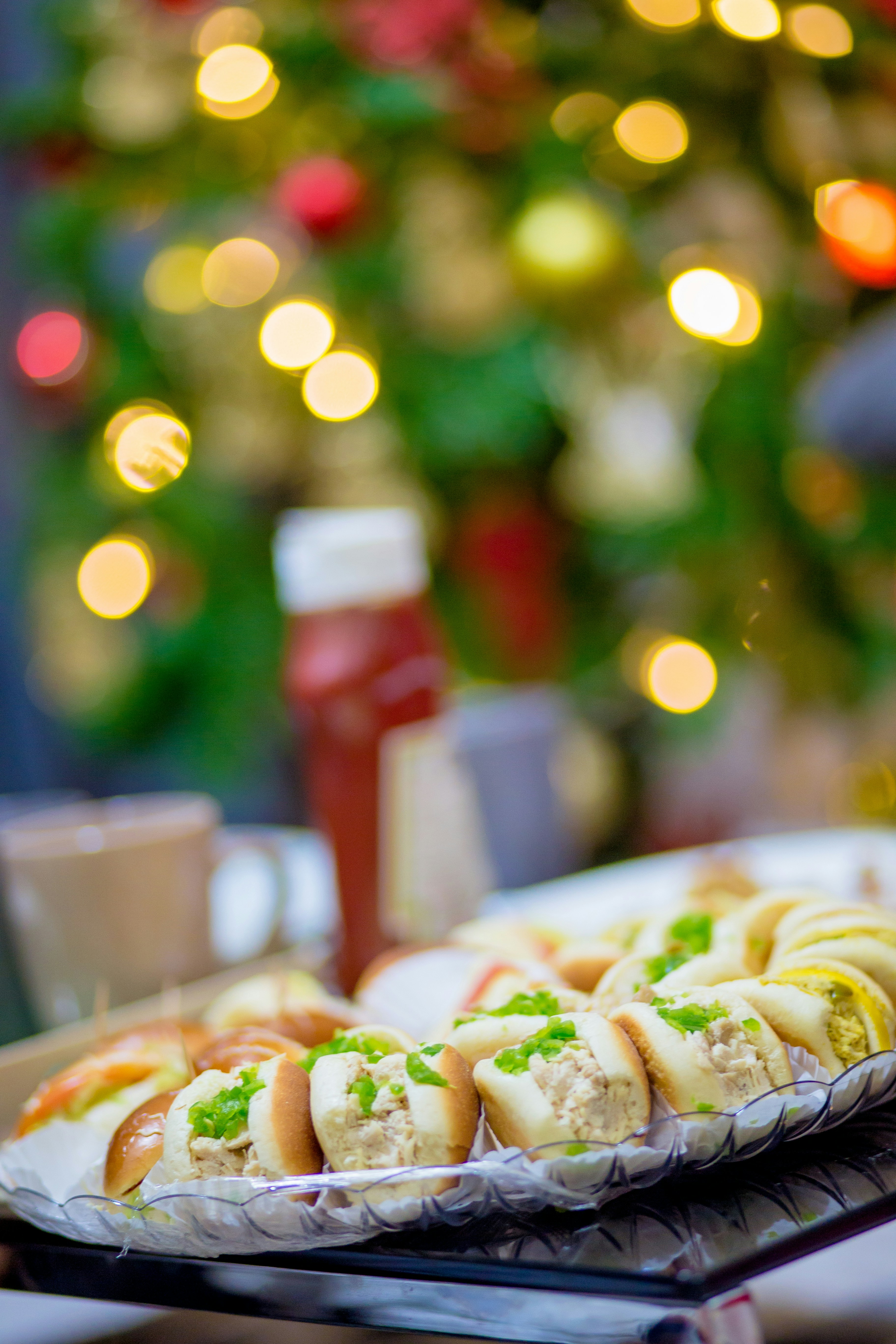 a tray of hotdogs on a table with a christmas tree in the background