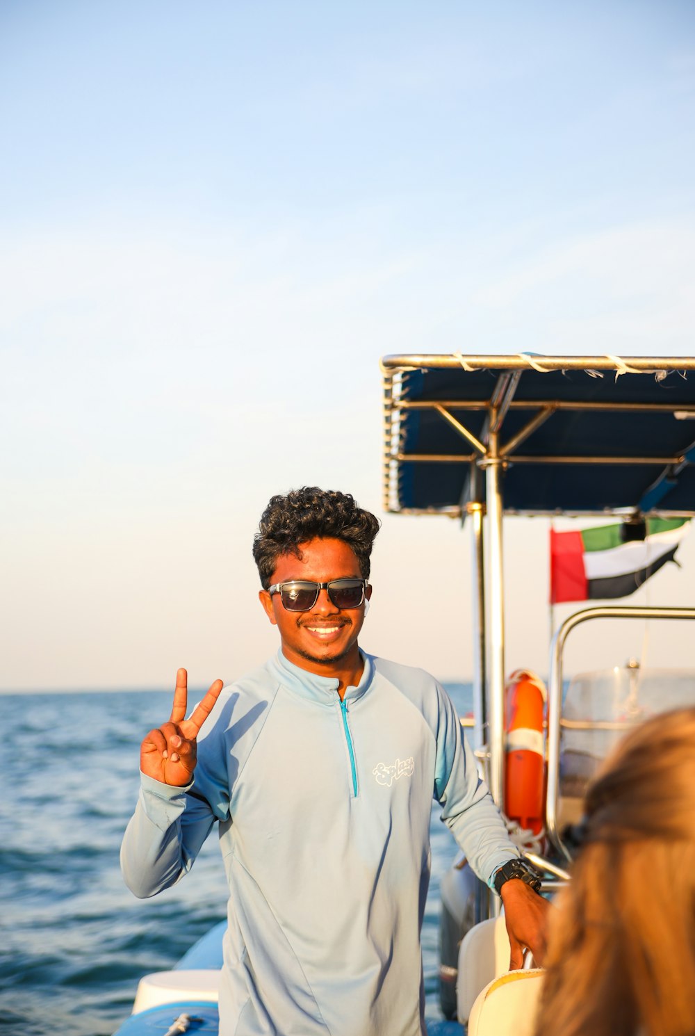 a man standing on a boat giving the peace sign