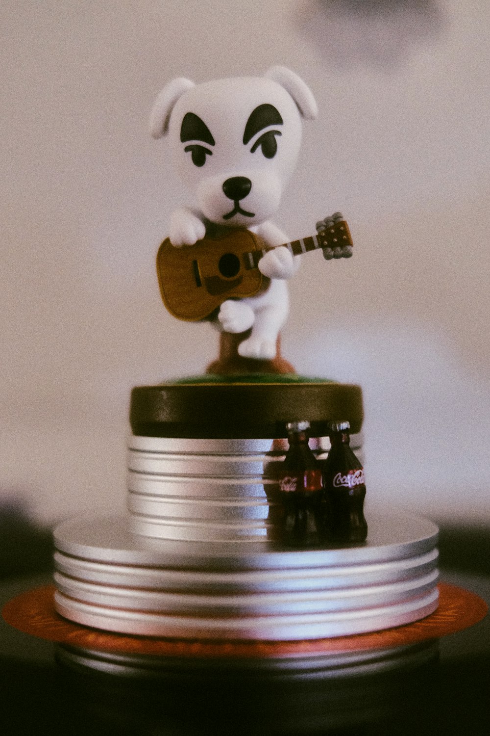 Un perro de juguete tocando una guitarra encima de una pila de monedas