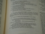 A close-up view of an open book page from the Bible, showing printed text in English. The text is clearly legible and features biblical verses with some words in bold and small numbers indicating verse numbers.