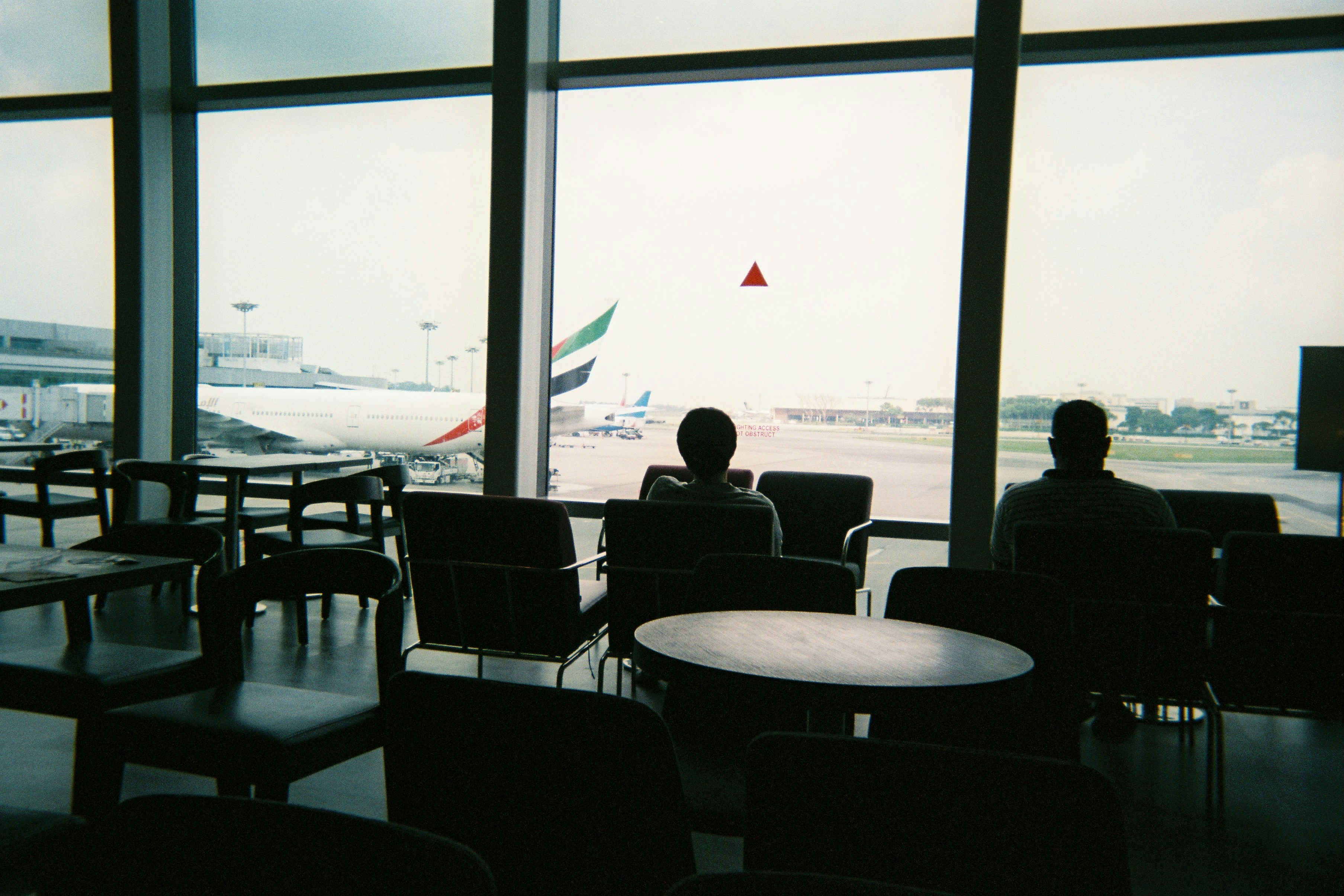 a couple of people sitting in chairs in front of a window, 