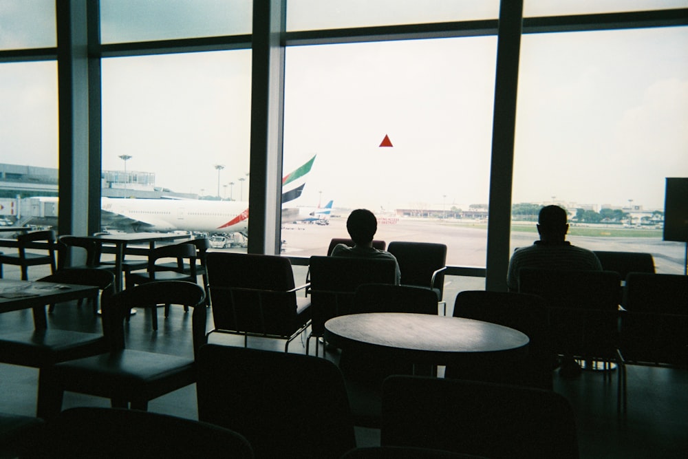 a couple of people sitting in chairs in front of a window