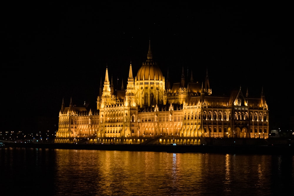 a large building lit up at night with water in front of it