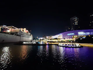 A vibrant cruise ship sailing at sunset with neon-colored lights glowing.