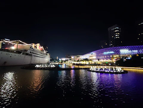 A vibrant cruise ship sailing at sunset with neon-colored lights glowing.