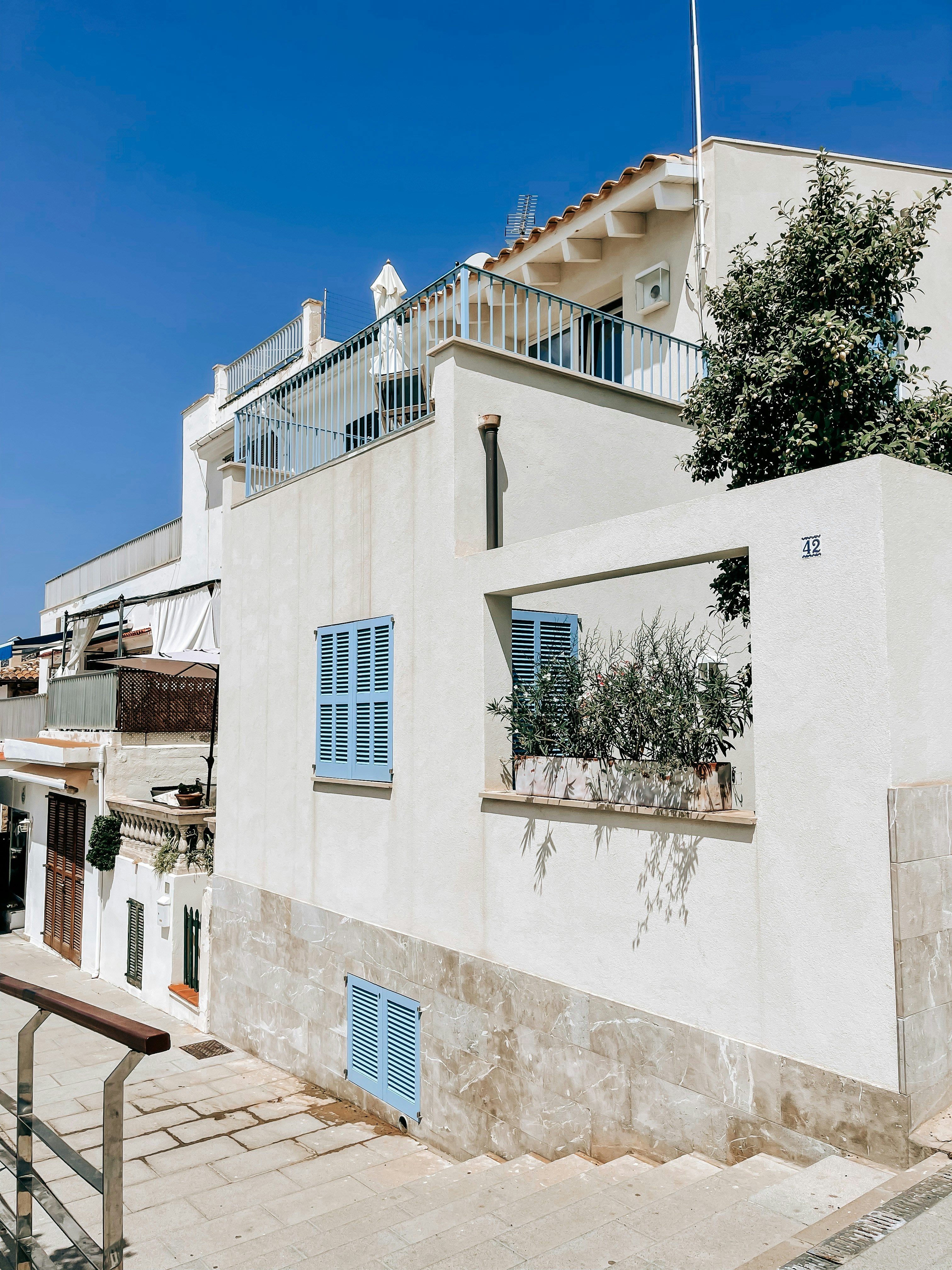 a white building with blue shutters and a balcony