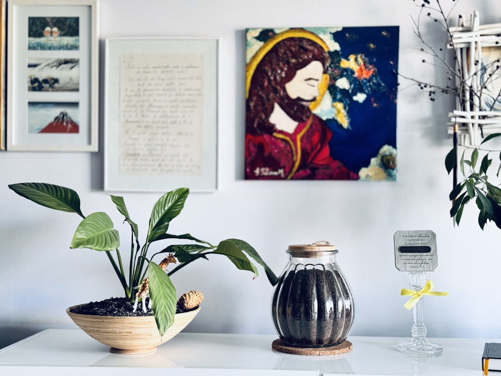 a white table topped with a potted plant next to a painting