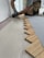 A person wearing gloves is installing wooden flooring. The focus is on the zigzag pattern of the wood pieces being laid down onto a layer of adhesive.